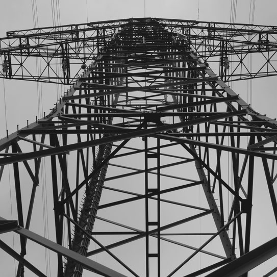black and white image of a transmission tower from a low angle to represent electrical