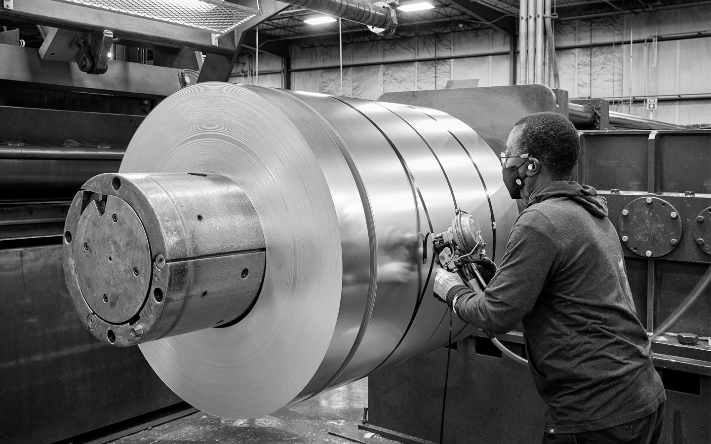 black and white image of an associate checking the quality of the steel coil